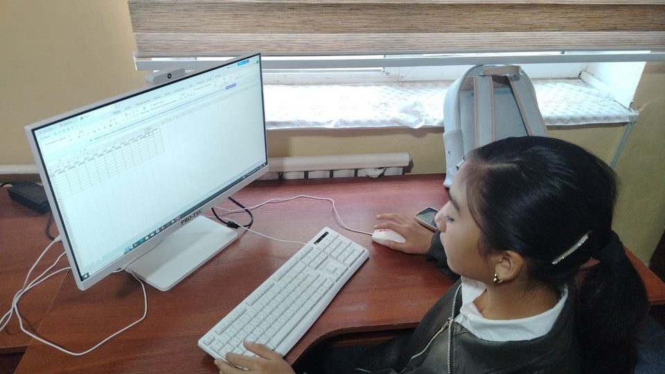 Qiz kompyuterda shug'ullanmoqda, ekranda Excel jadvali
